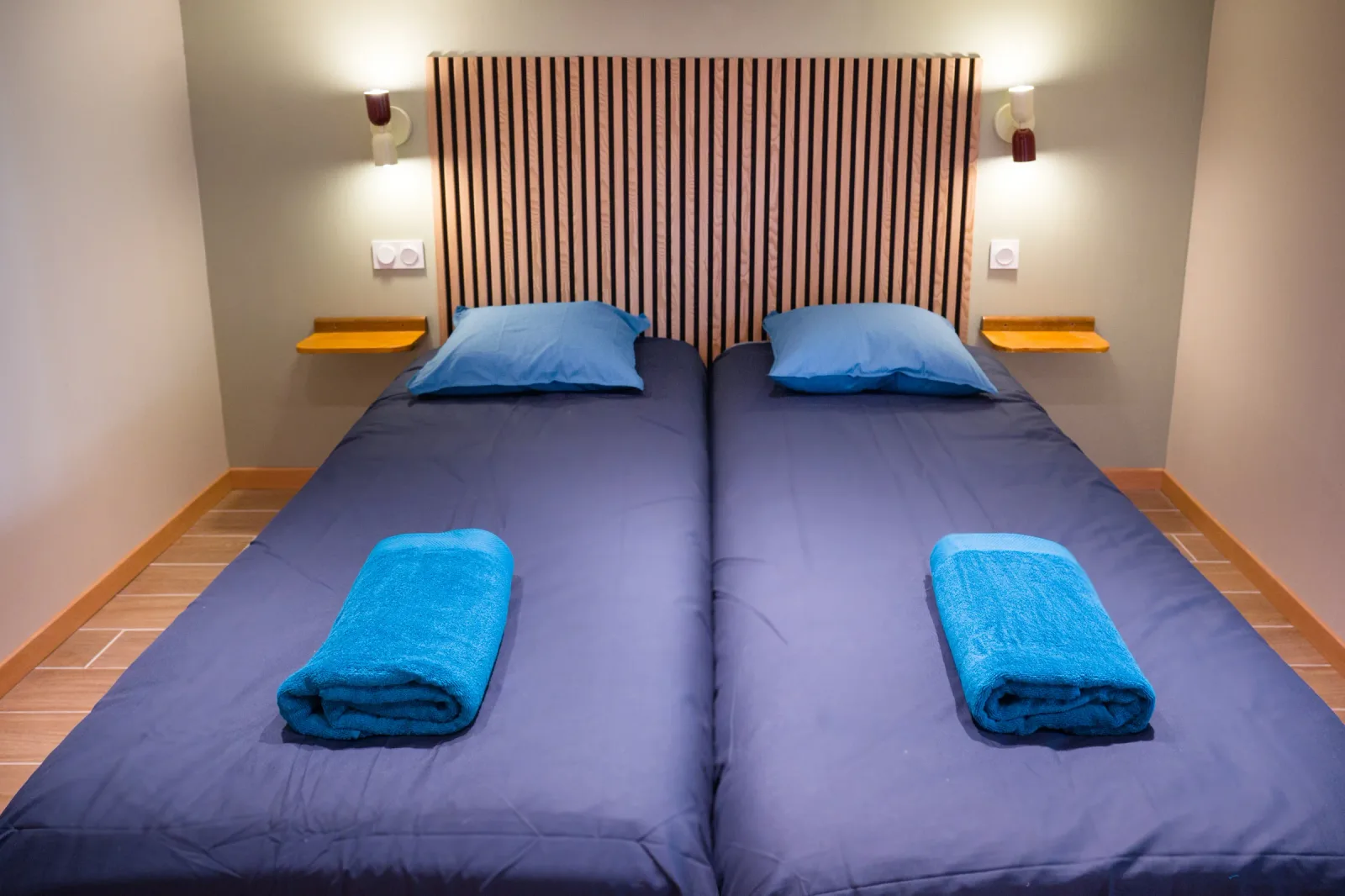 Chambre du studio avec deux lits jumeaux côte à côte et tête de lit en lattes bois
